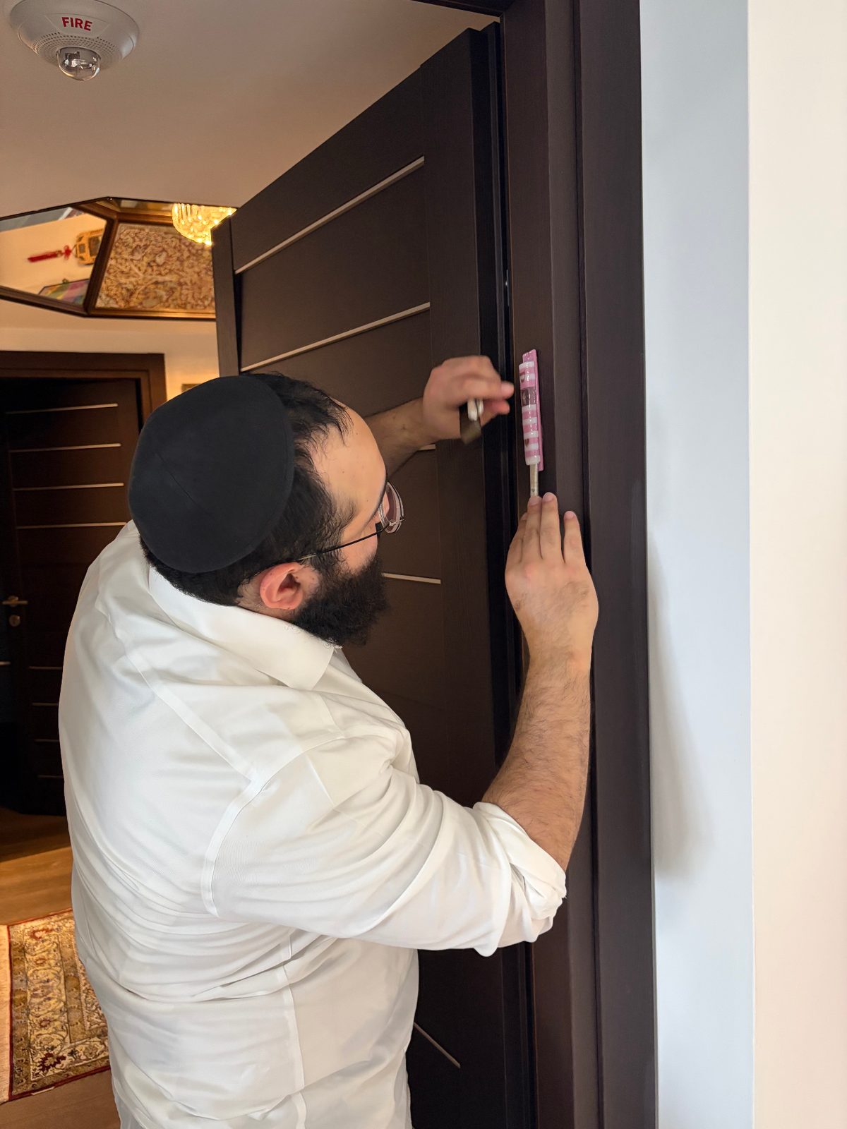 Rabbi Levi Backman, Certified Sofer STaM, installing a kosher mezuzah on a doorpost during a home visit in Miami